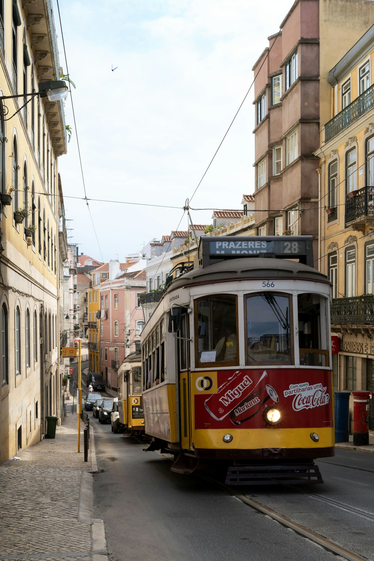 Bonde amarelo de Lisboa subindo rua estreita de paralelepípedos